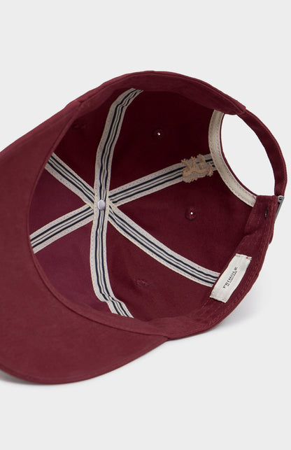 Maroon baseball cap with a white interior and brand label on a light gray background