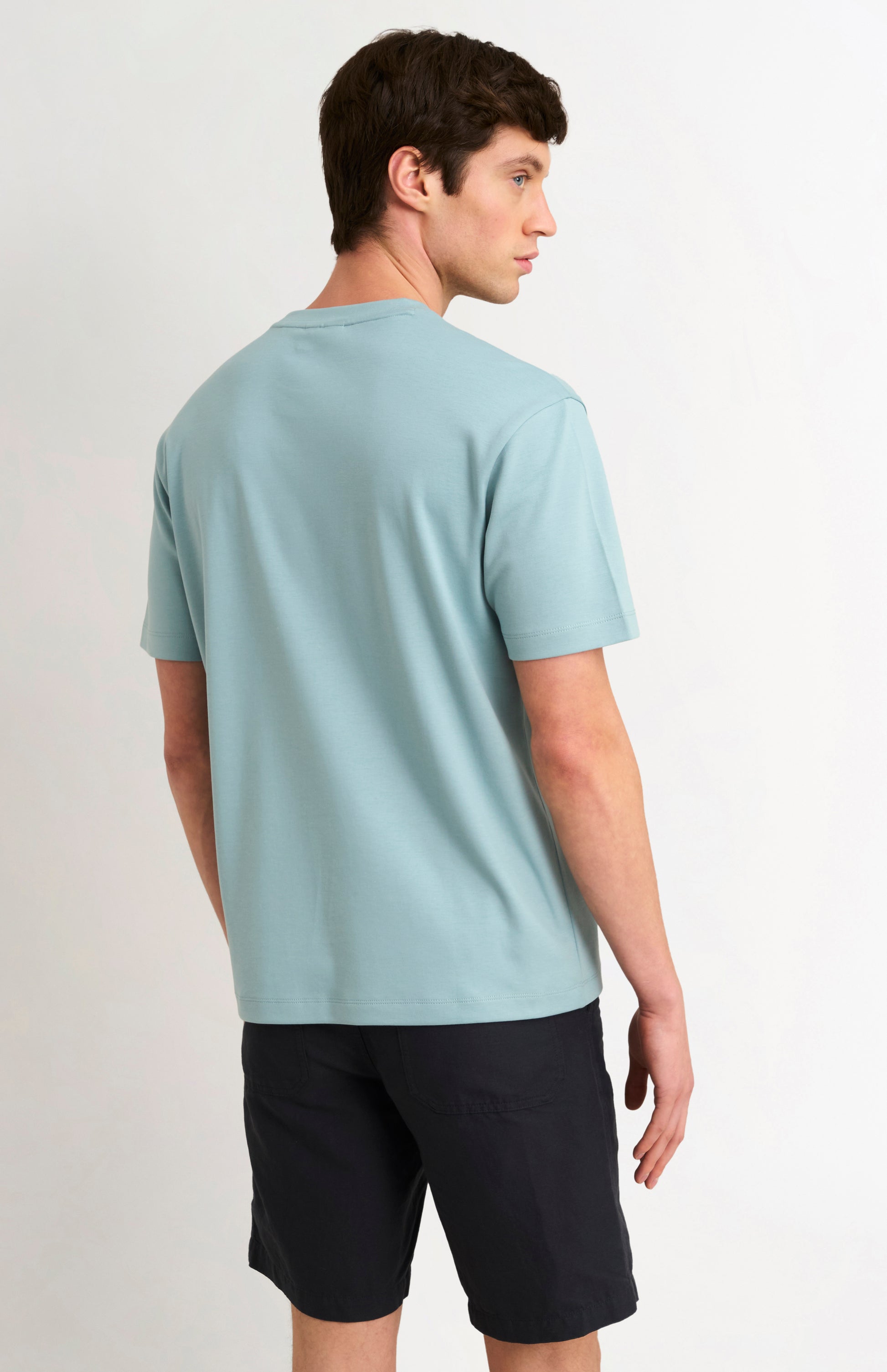 Man wearing a blue t-shirt and black shorts on a white background