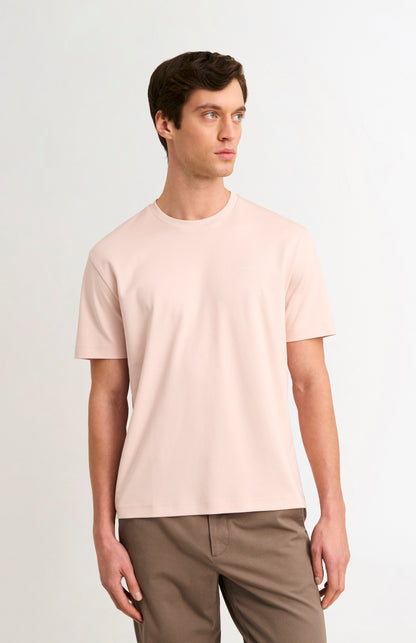 Man wearing a light pink t-shirt and beige trousers on a white background