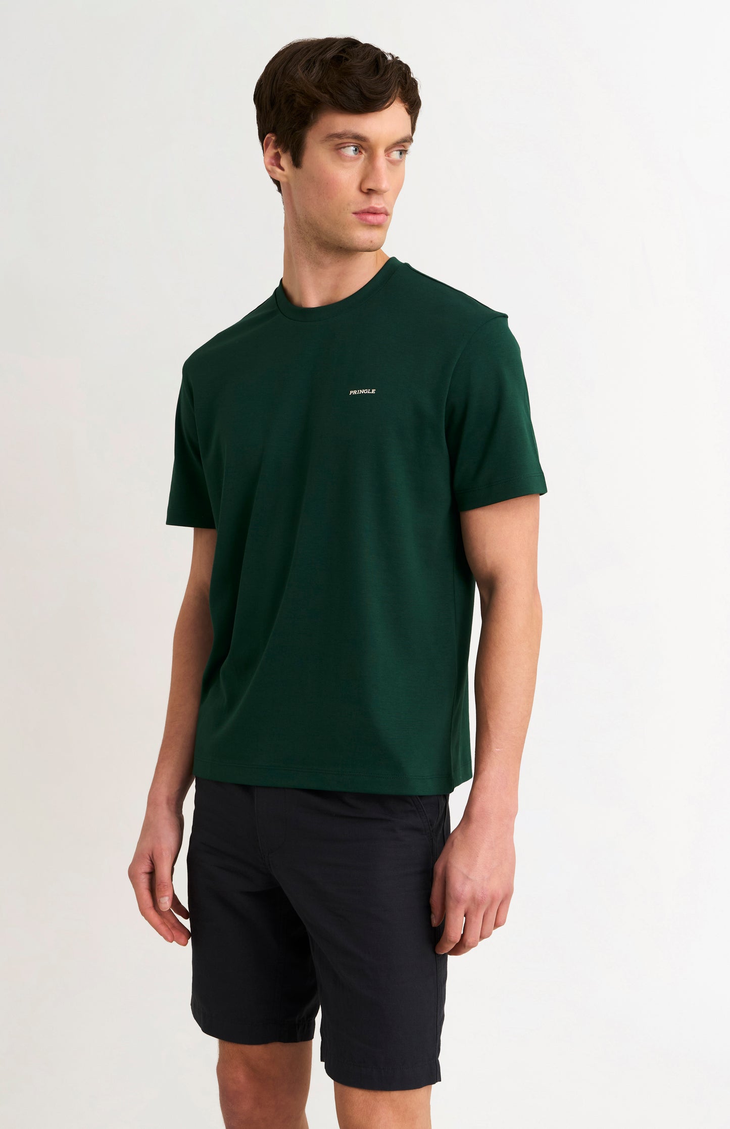 man wearing a dark green t-shirt and black shorts on a white background