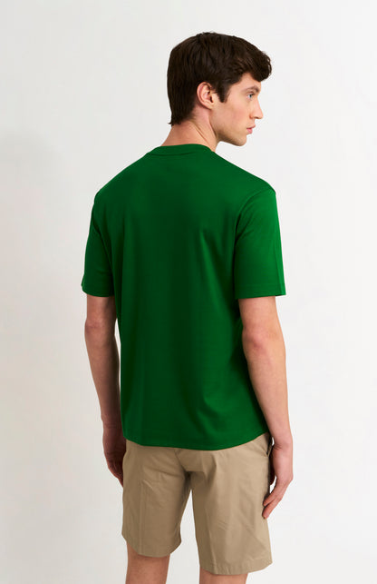 Man wearing a green t-shirt and beige shorts on a white background
