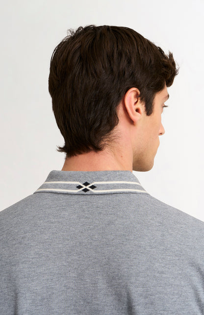 Man wearing a gray polo shirt with a brand logo on a white background