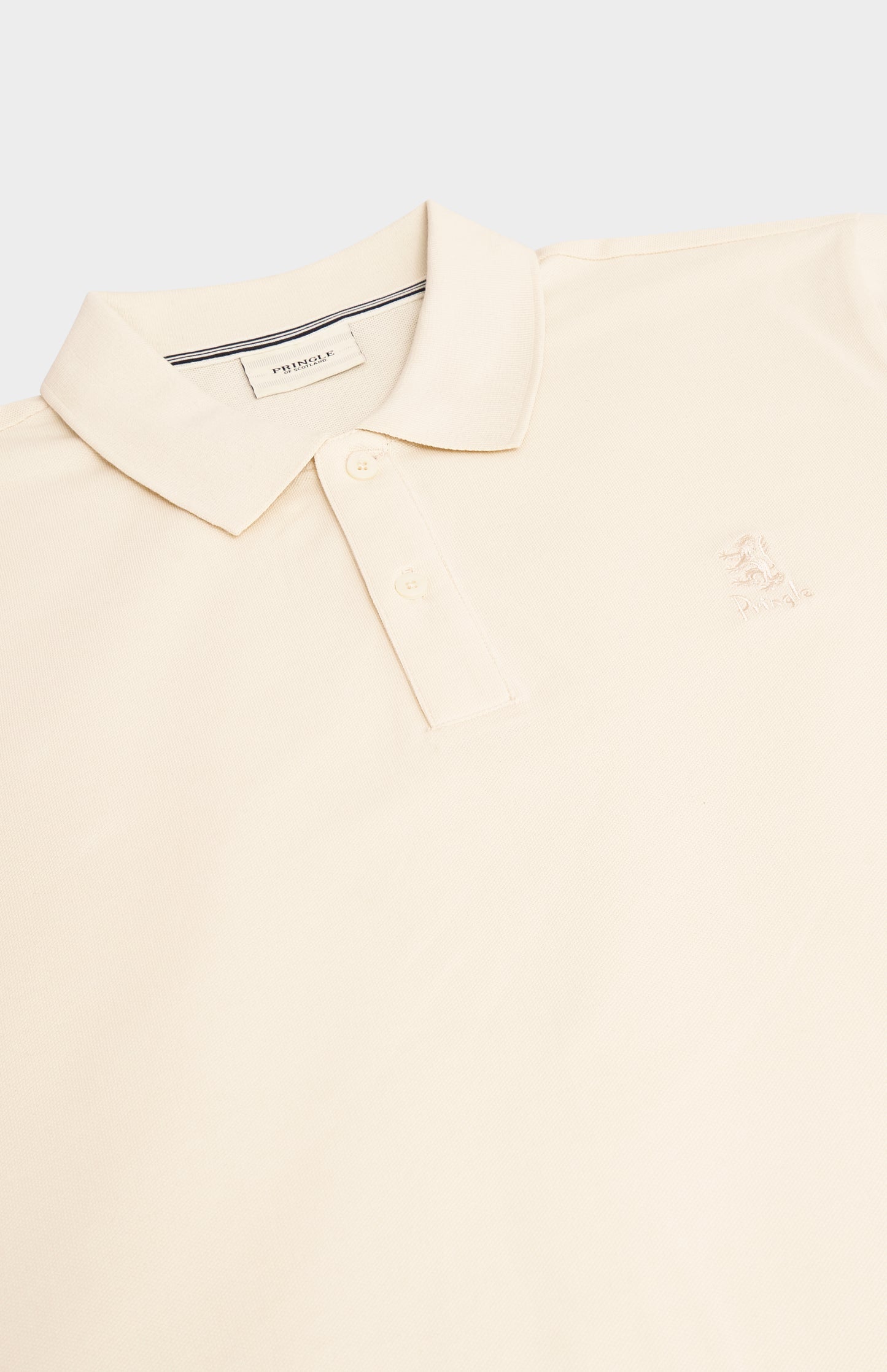A close-up of a light cream polo shirt with a classic collar, two-button placket, and a small embroidered logo on the left chest.