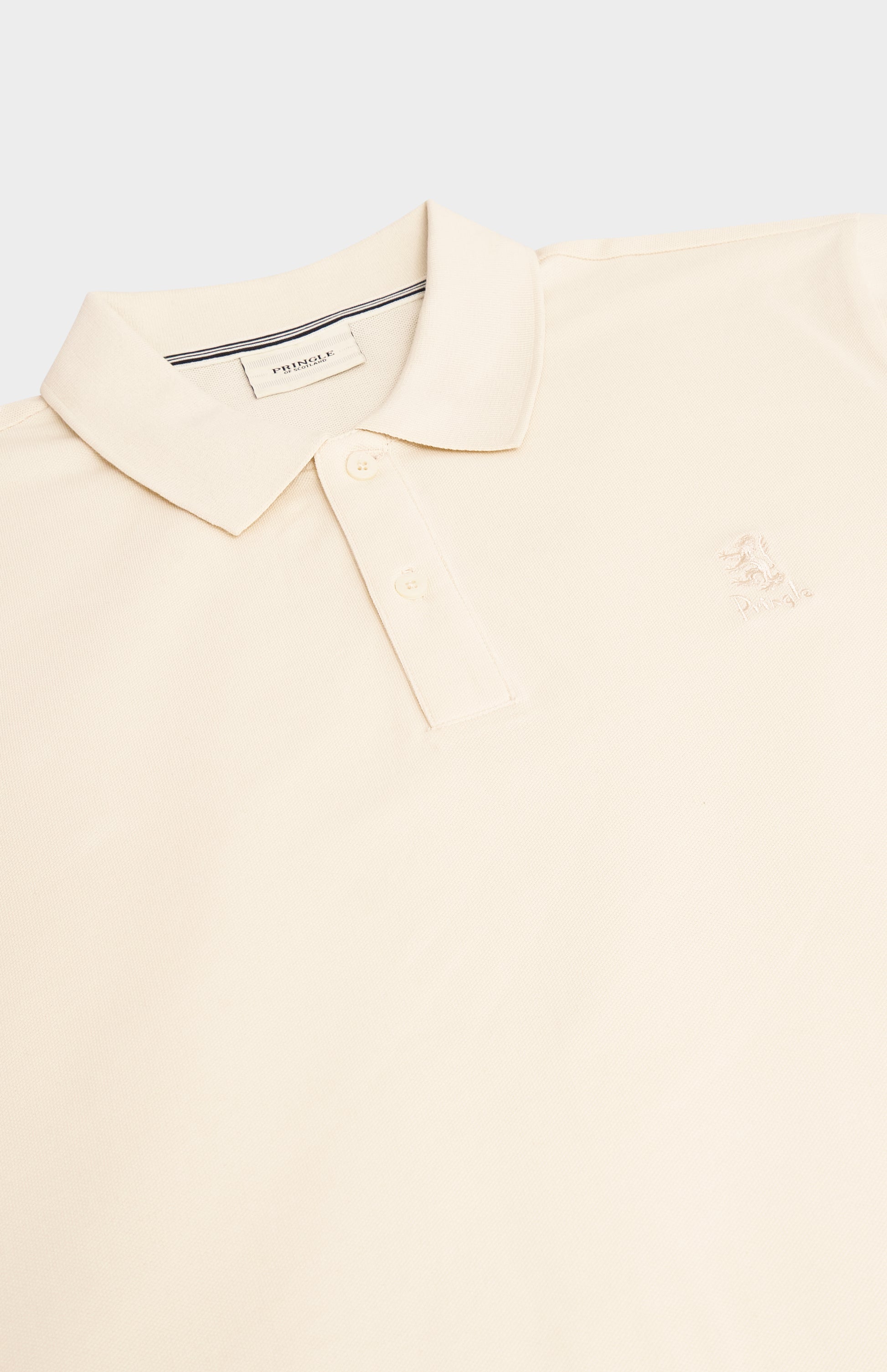 A close-up of a light cream polo shirt with a classic collar, two-button placket, and a small embroidered logo on the left chest.