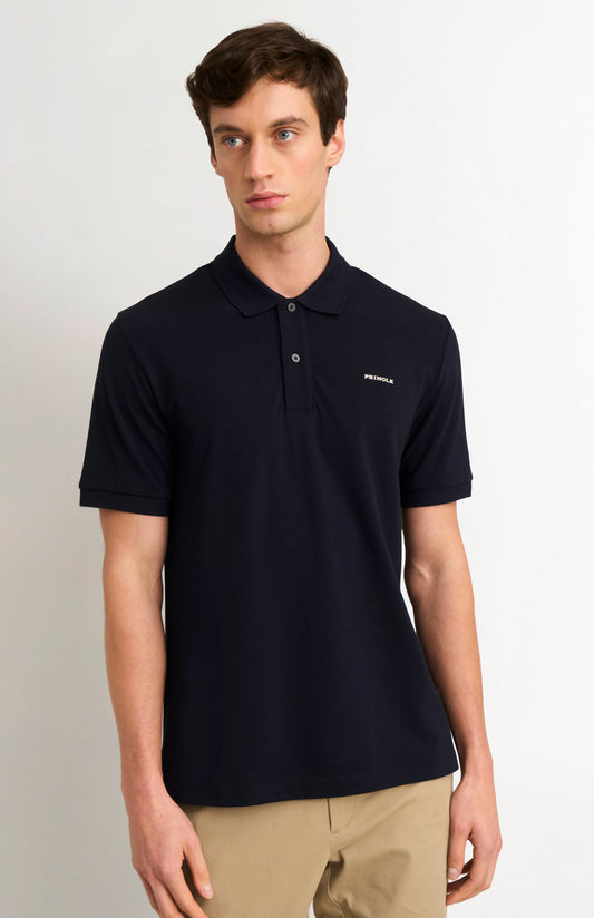 Man wearing a navy polo shirt with PRINGLE  logo on a light gray background