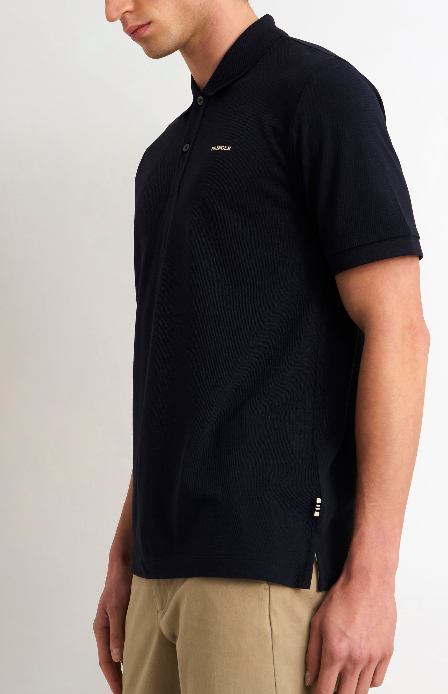 Man wearing a navy polo shirt with a visible brand logo on a light background