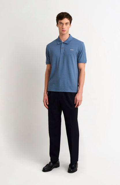 Man wearing a blue polo shirt with dark trousers on a white background