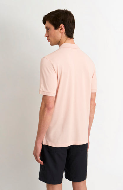 Man wearing a light pink polo shirt and black shorts on a white background