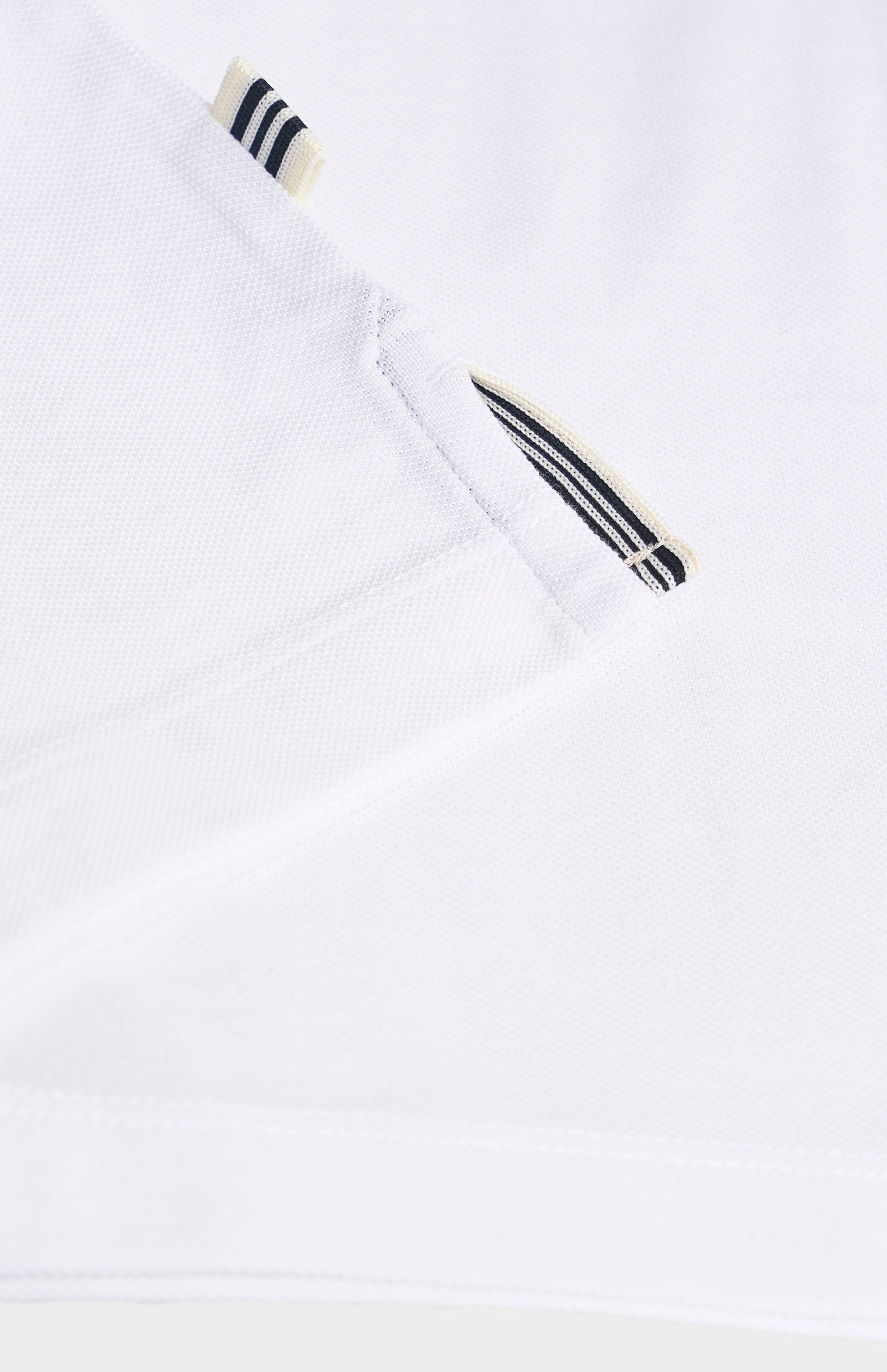 Close-up of a white polo shirt with black and white striped details on a light gray background