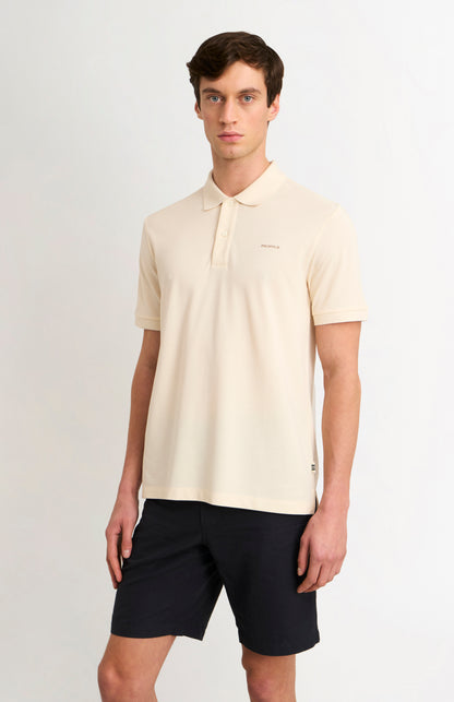 Man wearing a beige polo shirt and black shorts on a white background