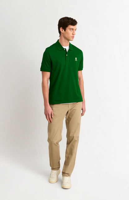 Man wearing a green polo shirt and beige pants on a white background