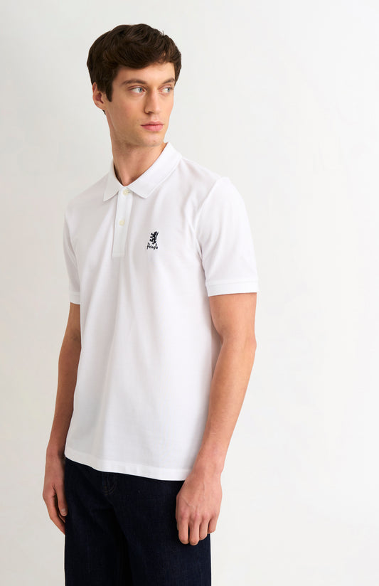 Man wearing a white polo shirt with a logo on a plain background
