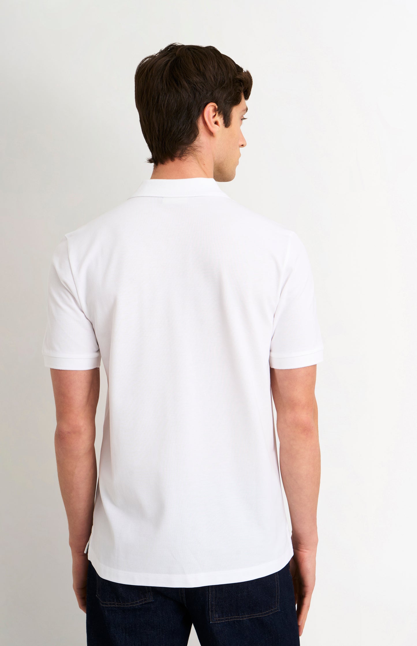 Man wearing a white polo shirt on a light gray background