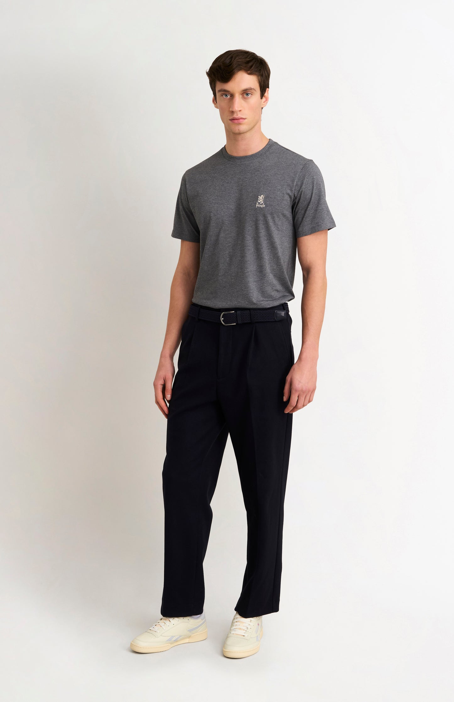 Man wearing a gray t-shirt and black pants on a white background