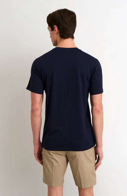 Man wearing a navy blue t-shirt and beige shorts on a plain background
