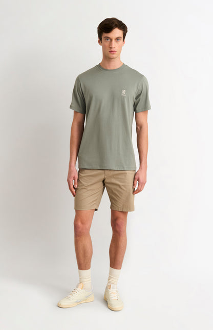 Man wearing a green t-shirt and beige shorts on a white background