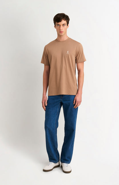 Man wearing a brown t-shirt and blue jeans