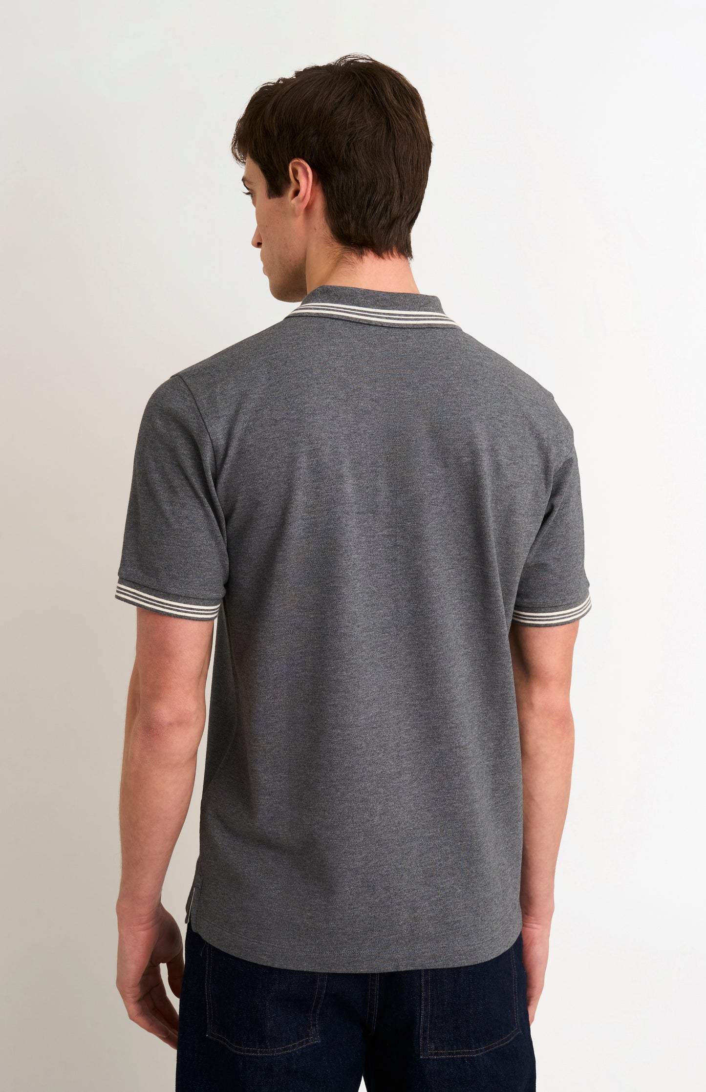 Back shot of model wearing a charcoal grey polo with white tipping details