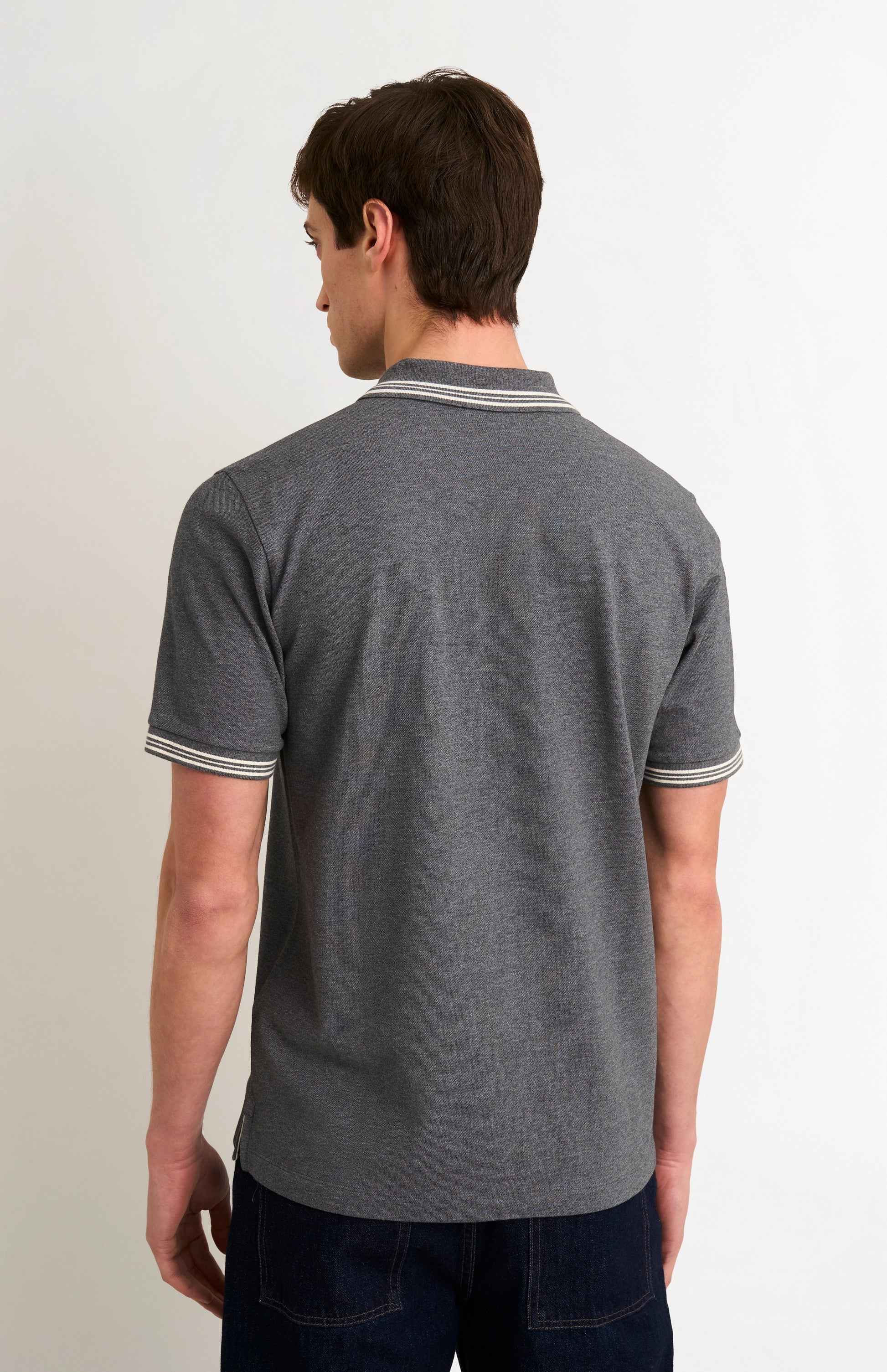 Back shot of model wearing a charcoal grey polo with white tipping details