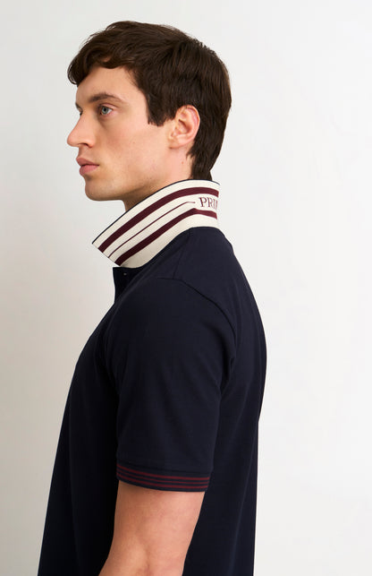 Model wearing a navy polo shirt with burgundy tipping details 