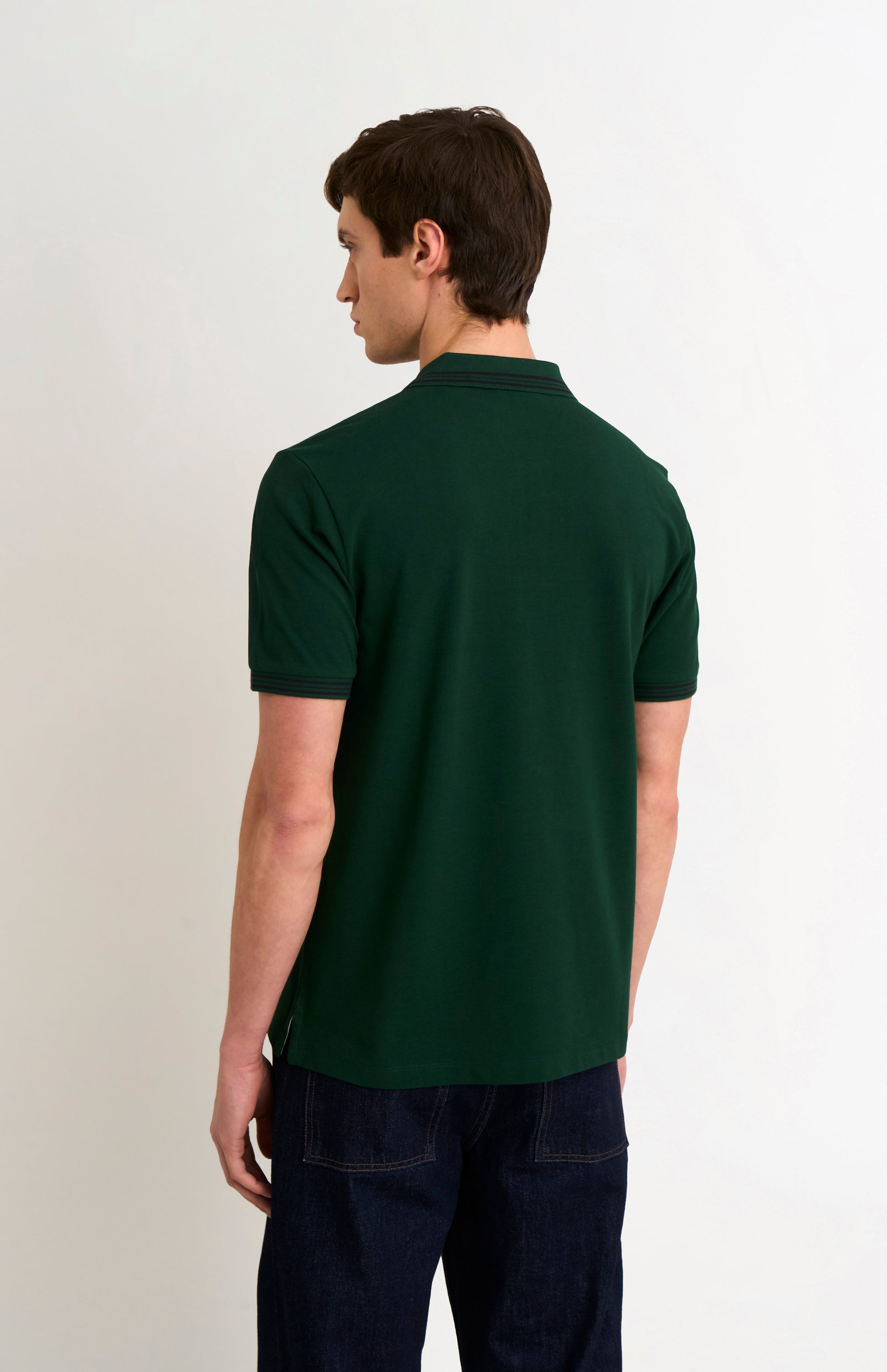 Back shot of model wearing a forest green polo with tipping details