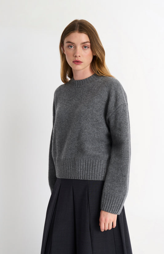 Woman wearing a gray sweater on a white background