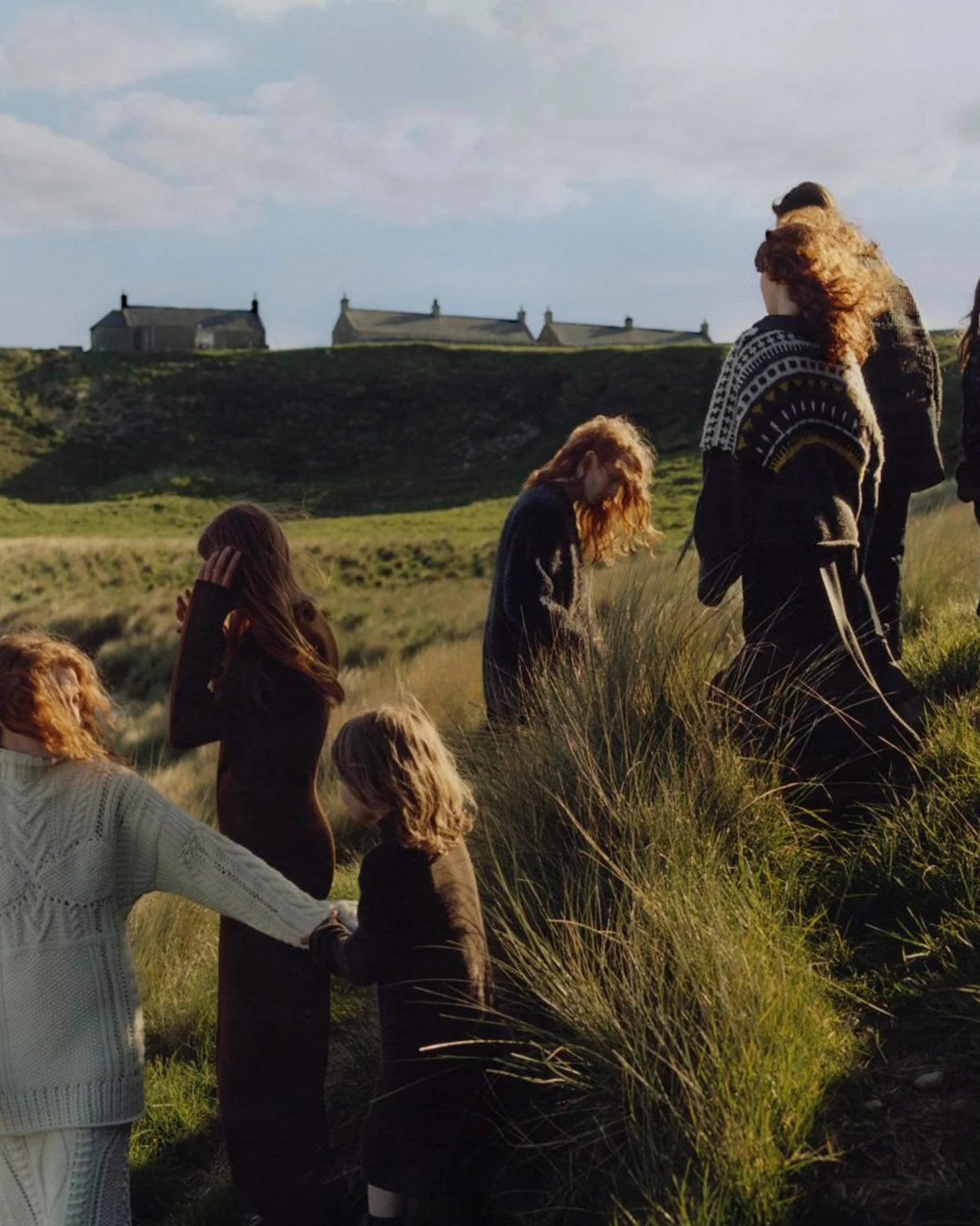 Group of models featuring Pringle of Scotland knitwear collection walking along a grassy path with a scenic background